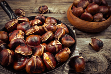Obraz premium chestnuts in a pan on a wooden background