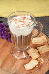 a cup of coffee with melted cream and cookies on a wooden tray