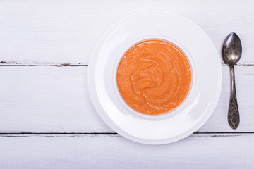 pumpkin soup in a white round plate and an iron spoon