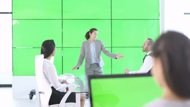  Business management team in a meeting with green screen video wall behind