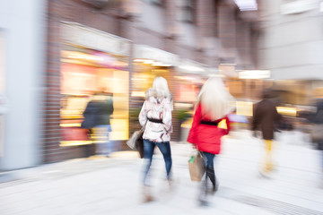 A young shoppers walking against shop window