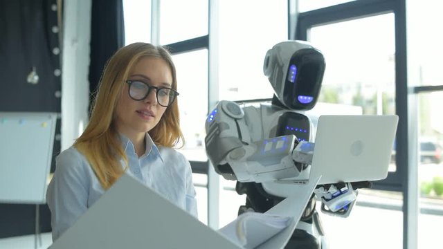 Young specialist working with robot in office