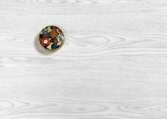 Small Metal Box Full of Buttons On a Wooden Background