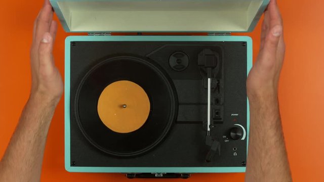 Top view hands putting record onto play on colorful vintage record player