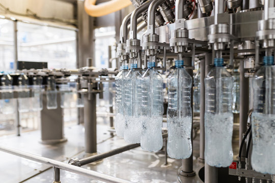 Bottling plant - Water bottling line for processing and bottling carbonated water into blue bottles. Selective focus. 
