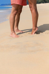 Legs of a kissing couple on a sea beach