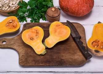 fresh pumpkin cut in half on a wooden kitchen board