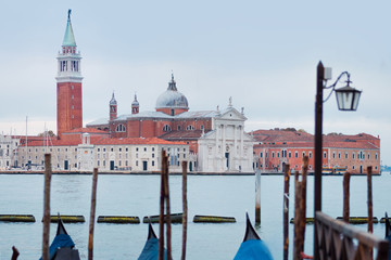 Fototapeta na wymiar Gondolas moored by Saint Mark square with San Giorgio di Maggiore church on the background