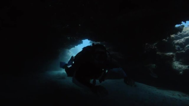 Scuba diver swimming through an underground cave, around a coral reef in Key Largo, Florida