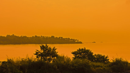 After sunset orange glow over the sun and sea, with silhouette of an island behind