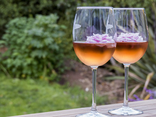 Two glasses of rosé wine and floating pink flowers
