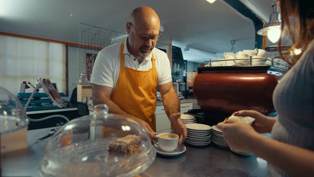  Cafe business owner serving coffee to customer & taking payment