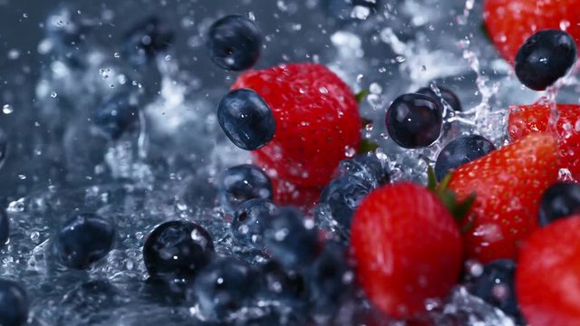 Slow motion fresh berries falling and splashing into clean fresh water