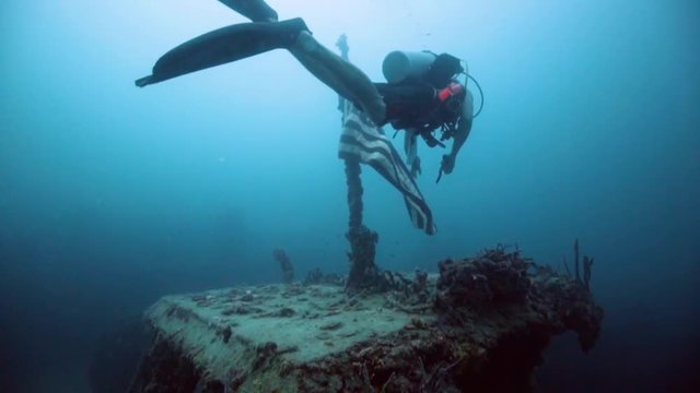 Underwater scuba diver holding up American Flag on the USS Spiegel Grove wreck, in the Florida Keys