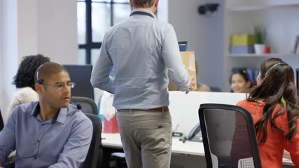  Happy businessman starting new job unpacking his belongings at his desk