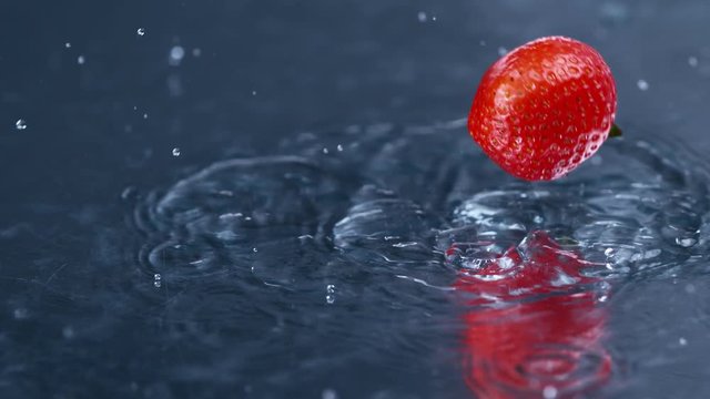 Fresh red strawberry falling and splashing into clean fresh water,