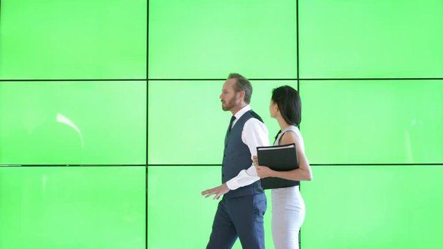  Business man & woman in discussion in modern office with green screen