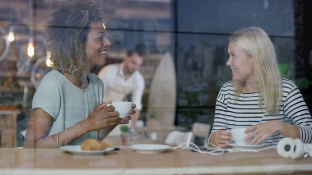 Young women chatting over coffees in city coffee shop