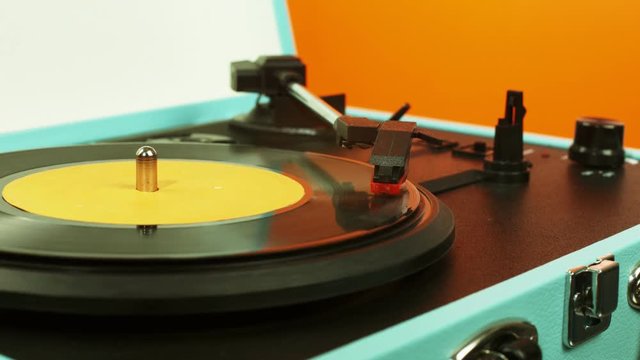  A record playing on colorful vintage record player, close up & in slow motion