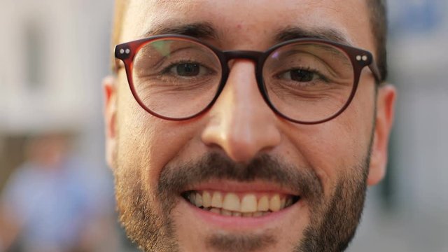 Close up portrait of a handsome young man smiling and winking to the camera. Blurred background. Slow motion