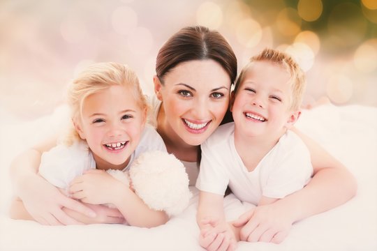 Composite image of happy mother and her children lying on a bed