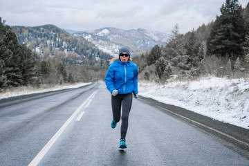 Woman running on snowy road in the Park.