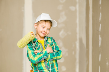 Happy young boy with paint roller looking a camera. Space for text