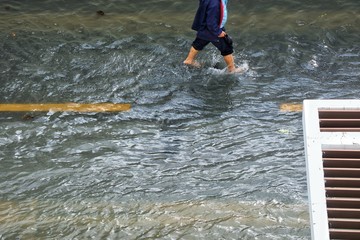 The men holding the shoes and walking on the streets flood. Soft focus.