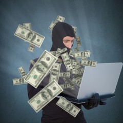 Composite image of burglar with balaclava hacking a laptop