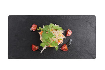 Isolated Too view of Diced salmon salad with avocado, tomato, onion, chilli, and coriander served in black rectangle stone plate on washi (Japanese paper). 