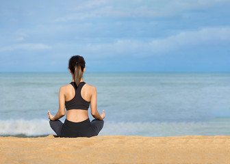 Fototapeta na wymiar Young healthy woman practicing yoga on the beach at sunrise