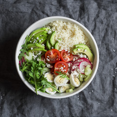 Couscous and fresh vegetables buddha bowl. Healthy, diet,  food concept. Cous cous, quail eggs, tomatoes, radish, arugula, avocado bowl on gray background, top view