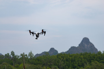 Fototapeta na wymiar DJI Inspire, a standard quad-copter flying into Langkawi Rainforest National Park. Low angle view.