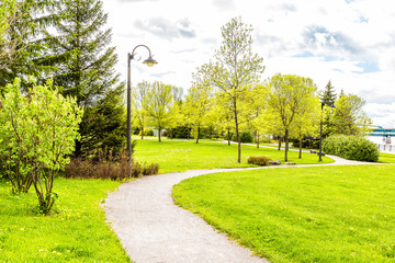 Sidewalk in green downtown city park in Saguenay, Canada, Quebec during summer with fjord river, bridge, boardwalk promenade