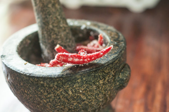 Close up to sweet spicy sauce with chili pepper and sugar in Mortar. Traditional cooking of spicy sauce in Thailand with mortar and pestle