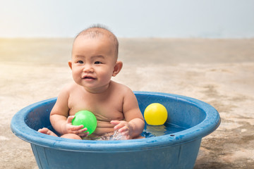 Cute New Born Baby playing ball in the plastic basin during shower,children learning