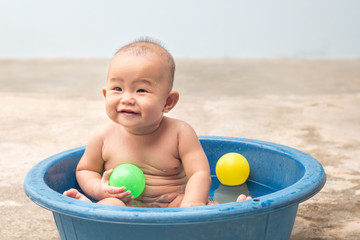 Cute New Born Baby playing ball in the plastic basin during shower,children learning