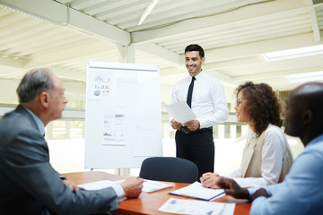 Happy speaker listening to opinion of one of colleagues after making report by whiteboard