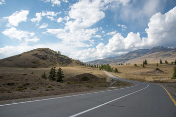 Asphalt winding road in the mountainous area in the summer and sky with clouds