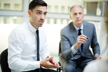 Young and mature businessmen talking out what they think about presentation