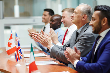 Row of delegates clapping their hands after successful speech of colleague