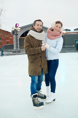 Fototapeta na wymiar Cheerful affectionate dates in skates and winterwear spending leisure together