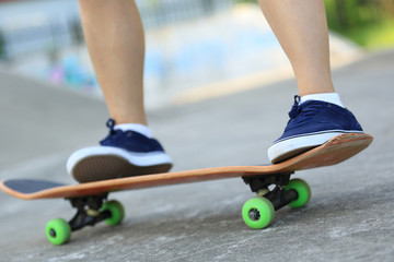 Skateboarder legs riding skateboard at skatepark