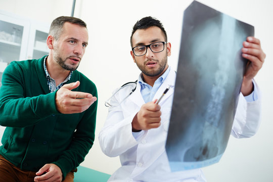 Patient and clinician discussing x-ray image of spinal cord