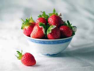 Picked strawberries in a bowl on white tablecloth