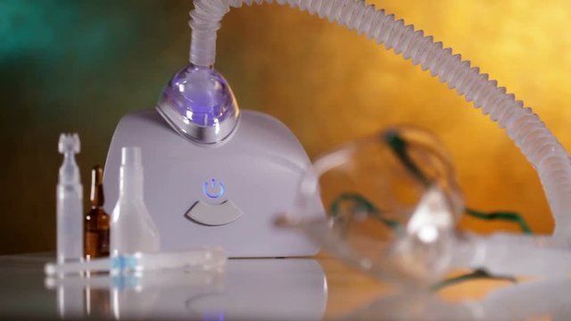 Hand turning on nebulizer inhaler device with vapour being generated - rack focus, static camera