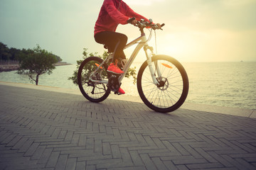 Fototapeta na wymiar young woman cyclist cycling at sunrise seaside