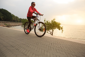 Fototapeta premium young woman cyclist cycling at sunrise seaside
