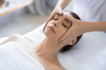 Obraz na płótnie Canvas Young woman having anti-stress facial massage in salon at spa resort