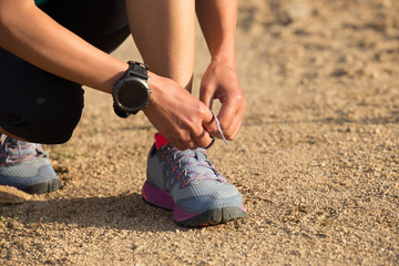 woman runner tying shoelace on dirt road